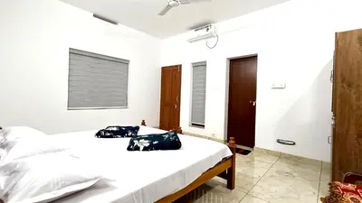 two beds in a bedroom with white walls at Pavans Rainy Days Home Stay in Athirappilly