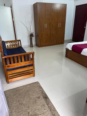 a bedroom with a bed and a chair and cabinets at Wayanad Midnight Farmhouse in Sultan Bathery