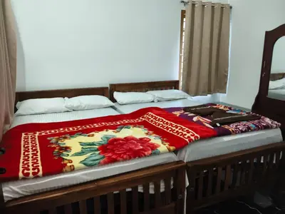 a bed with a red blanket on top of it at Palm view 2 in Kanthalloor