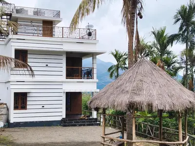 a white house with a straw roof and palm trees at Palm view 2 in Kanthalloor