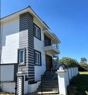 a white house with stairs and a balcony at Hill Grove By Brown Tree Resorts in Ooty