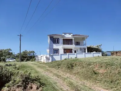 a white house on a hill with a dirt road at Hill Grove By Brown Tree Resorts in Ooty