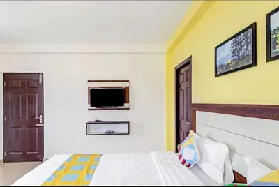 a bedroom with a bed and a tv on the wall at Hill Grove By Brown Tree Resorts in Ooty