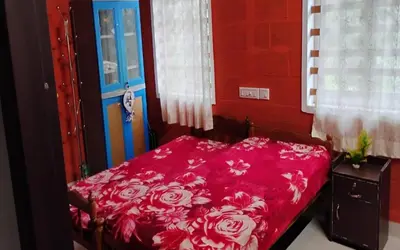 a bedroom with a bed with a red sheets and a blue door at Kadavath Homestay in Ernakulam