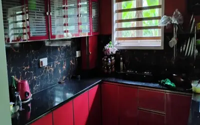 a kitchen with red cabinets and a black counter top at Kadavath Homestay in Ernakulam