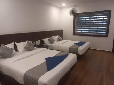 two beds in a room with a window at SUROOR Recidency in Virajpet
