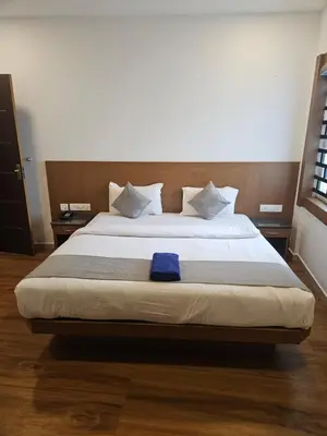 a bedroom with a large bed with a blue towel on it at SUROOR Recidency in Virajpet