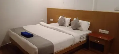 a bed with white sheets and pillows in a room at SUROOR Recidency in Virajpet