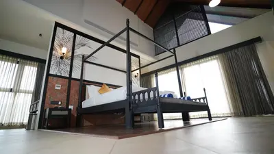 a bedroom with a canopy bed in a room with windows at Manjoora Saddles Resorts & Spa in Padinjarathara