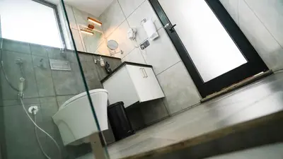 a bathroom with a toilet and a window and a mirror at Manjoora Saddles Resorts & Spa in Padinjarathara