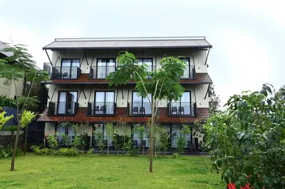 a large building with windows and a yard at Manjoora Saddles Resorts & Spa in Padinjarathara