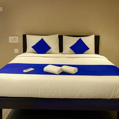 a bed with blue pillows and two remote controls on it at Hotel Karpagam Lodging House Nr Railway Station & Gandhipuram bus stand in Coimbatore