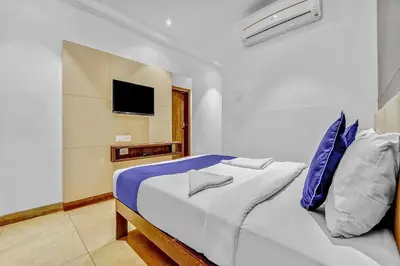 a white bedroom with a bed with blue pillows at Hotel Karpagam Lodging House Nr Railway Station & Gandhipuram bus stand in Coimbatore