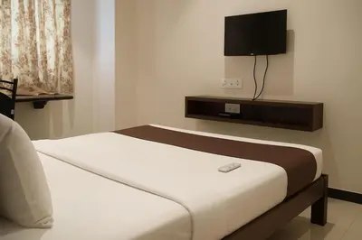 a room with two beds and a tv on the wall at Hotel Karpagam Lodging House Nr Railway Station & Gandhipuram bus stand in Coimbatore