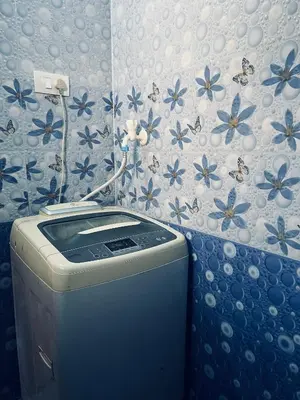 a washing machine in a bathroom with blue flowers on the wall at Athithi AC Studio Flat By Shivalaya Stays in Podanūr
