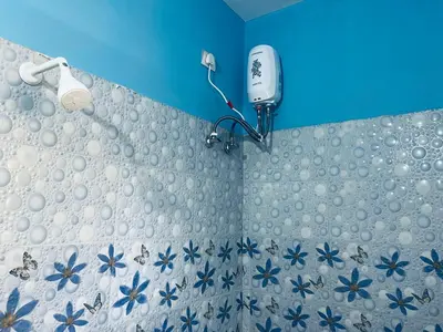 a bathroom with a shower with a blue wall at Athithi AC Studio Flat By Shivalaya Stays in Podanūr