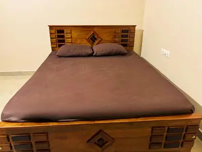a wooden bed with two pillows on top of it at Saraa Homes Fully Furnished 2BHK Apartment in Kulattūr