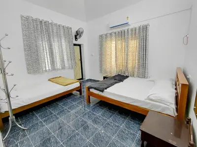 a bedroom with two beds and a table and a window at Guruvayur Agraharam Homestay in Guruvāyūr
