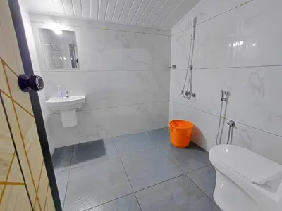 a white bathroom with a toilet and a sink at Guruvayur Agraharam Homestay in Guruvāyūr