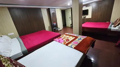 a small room with two beds and a tv at Mananya Cottage Ooty in Ooty