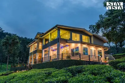 a large house with large windows on a hill at StayVista at Sande's Farview with Bonfire in Coonoor
