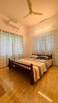 a bedroom with a bed with blue curtains and a fan at Niel Valley Homestay - Poomala in Mulagunnathukāvu