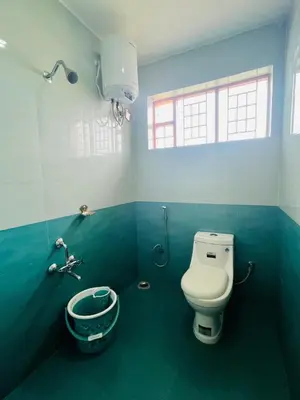 a bathroom with a toilet and a bucket in it at Green Hill in Coonoor