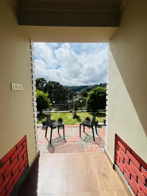 a view from a room with two benches on a patio at Green Hill in Coonoor