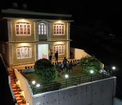 a group of people standing outside of a house at night at Green Hill in Coonoor