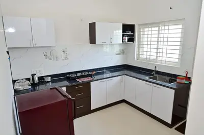 a kitchen with white cabinets and a black refrigerator at Oasis Service Apartments in Mysore
