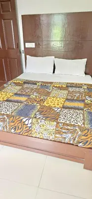 a bed with a wooden headboard with a blanket on it at The Green Regency Annexe in Munnar