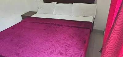 a bed with a pink blanket on top of it at The Green Regency Annexe in Munnar