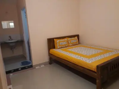 a bedroom with a bed with yellow sheets and a mirror at NectorNest in Kodaikānāl