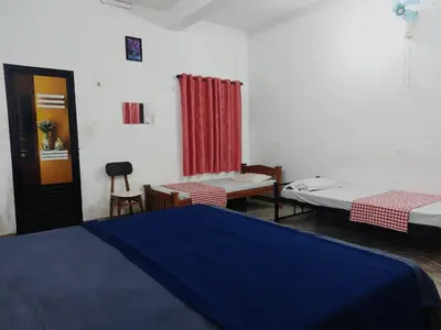 a room with two beds and a table and chairs at Fathima Arcade Lodge