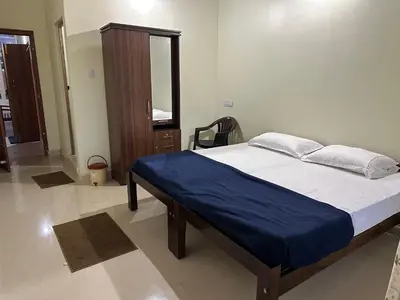 a bedroom with a bed with blue sheets and a mirror at River point homestay in Kushālnagar
