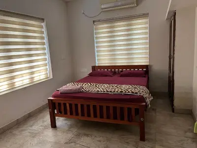 a bed in a room with two windows at Dragster Homes Alwaye in Alwaye
