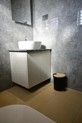 a bathroom with a white sink and a stool at Hotel Shellmark in Elivāla