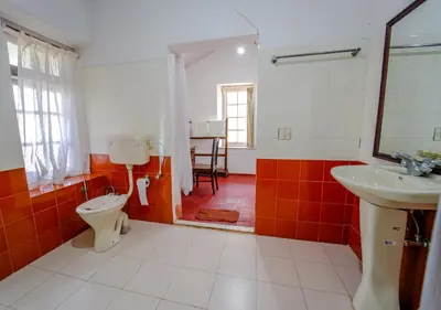 a bathroom with a toilet and a sink and a mirror at Arivikad Tea Bungalow Munnar By VOYE HOMES in Munnar