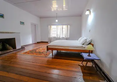 a white room with a bed and a fireplace at Arivikad Tea Bungalow Munnar By VOYE HOMES in Munnar