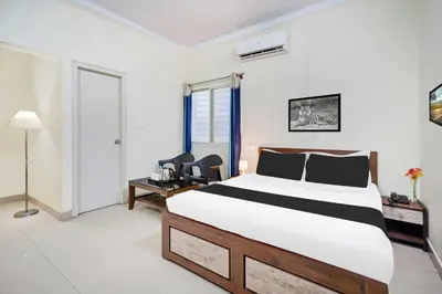 a bedroom with a bed and a desk and chairs at Collection O Mysore Shri Lakshmikantha Swamy Temple in Mysore