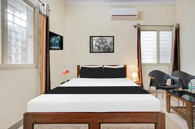 a bedroom with a bed and two chairs at Collection O Mysore Shri Lakshmikantha Swamy Temple in Mysore
