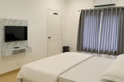 a white bedroom with a bed and a flat screen tv at The Nest in Trichūr