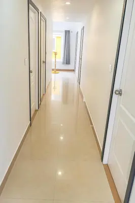 a hallway with white walls and white doors and a tile floor at The Nest in Trichūr