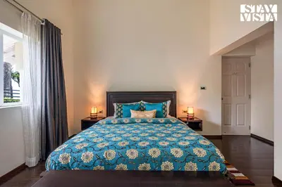 a bedroom with a blue bed with two lamps at StayVista at Farview Presidential Suite with Lawn, Bonfire & Bathtub in Kotagiri