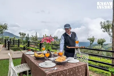 an elderly man standing at a table with food at StayVista at Farview Presidential Suite with Lawn, Bonfire & Bathtub in Kotagiri