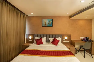 a bedroom with a bed with red pillows and a desk at Ascot Hotel Calicut in Calicut