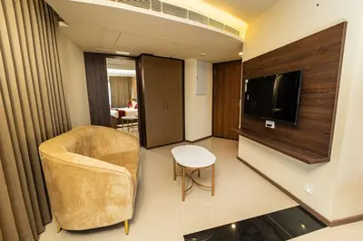 a living room with a chair and a television at Ascot Hotel Calicut in Calicut