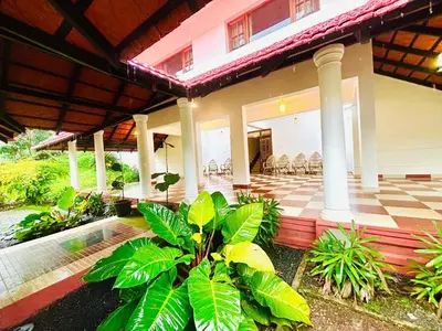 a house with a porch and a patio with chairs at WAYANAD RESORT VILLA Service in Meppādi