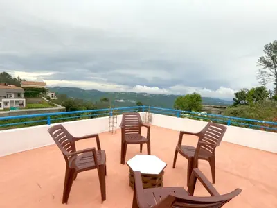 a table and chairs on a balcony with a view at HIGHLAND Hills in Coonoor