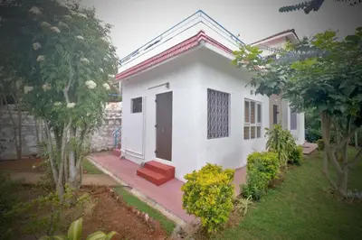 a white house with a red door in a yard at HIGHLAND Hills in Coonoor